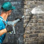 House Brick Wall Washing Using Pressure Washer. Caucasian Worker in His 30s.